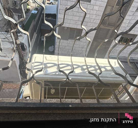 מזגן מותקן מחוץ לחלון עם סורגים